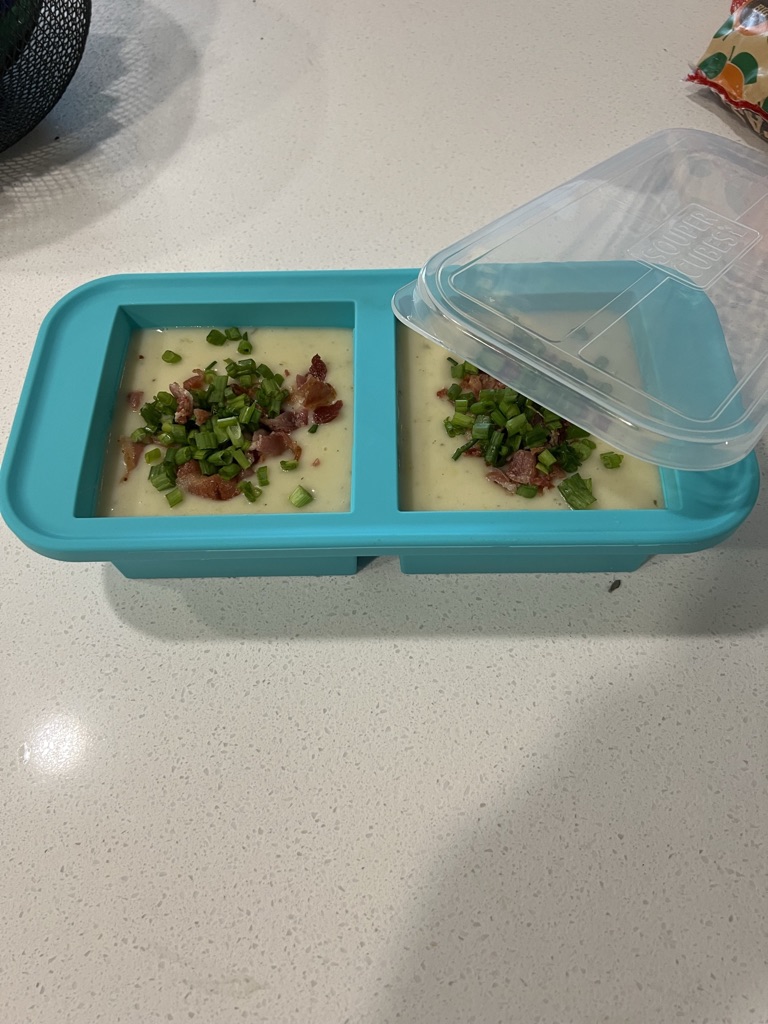 Creamy prepared soup portioned into two Souper Cubes compartments and topped with bacon and green onions.